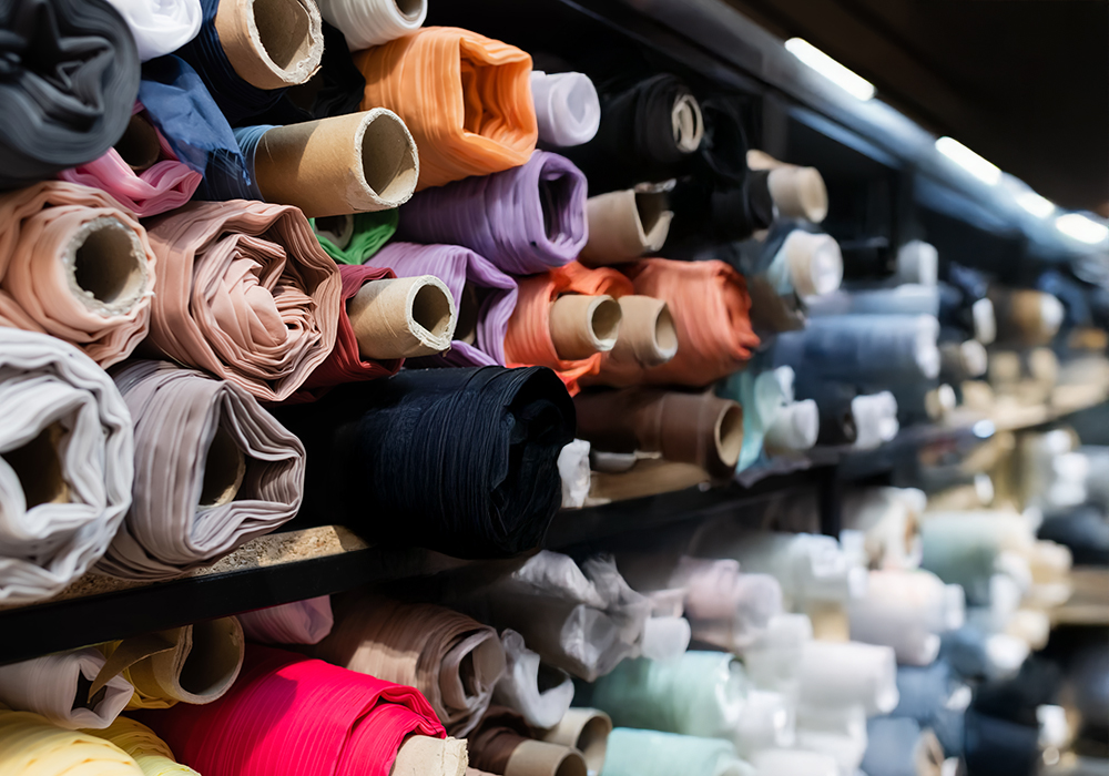 cropped view of salesperson choosing between colorful fabric rol